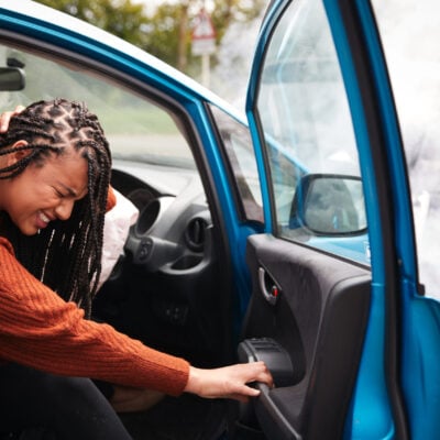 Female Motorist With Whiplash Injury In Car Crash Getting Out Of Vehicle