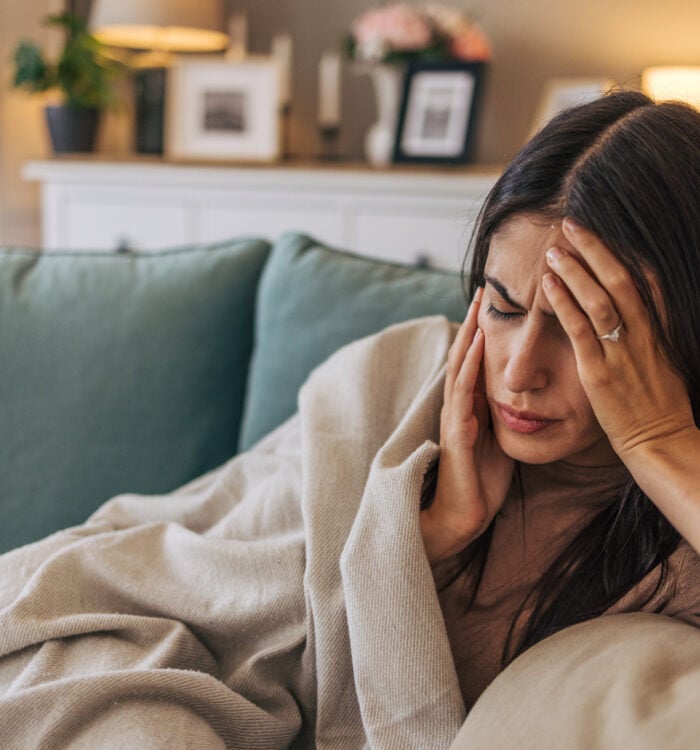 A young woman lying on the sofa in the living room, feeling sick.